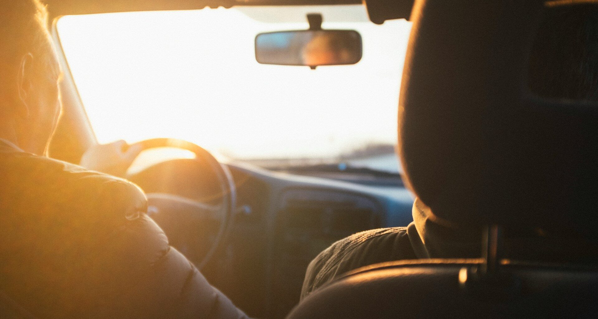 Osoba řídící auto při západu slunce.