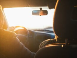 Osoba řídící auto při západu slunce.