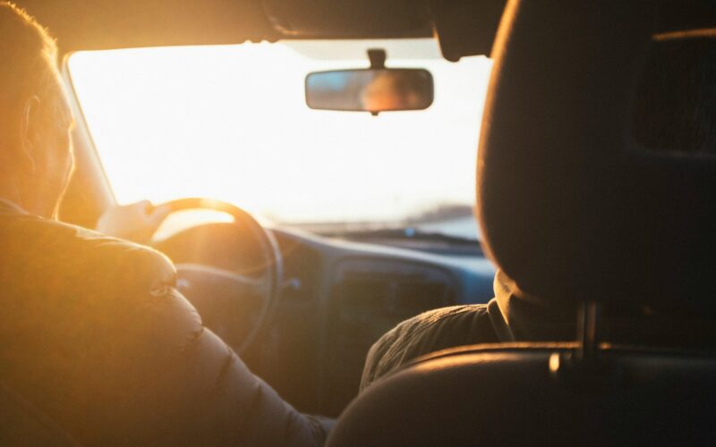 Osoba řídící auto při západu slunce.