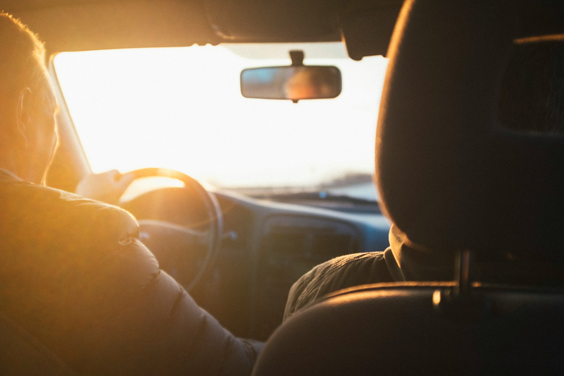 Osoba řídící auto při západu slunce.