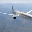 Letadlo společnosti Etihad Airways letí nad krajinou s horami v pozadí.