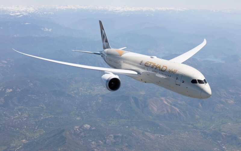 Letadlo společnosti Etihad Airways letí nad krajinou s horami v pozadí.
