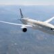 Letadlo společnosti Etihad Airways letí nad krajinou s horami v pozadí.