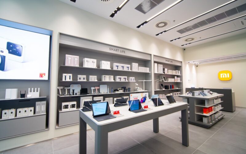 Moderní obchod s elektronikou Xiaomi, zobrazuje vystavené tablety a příslušenství na policích, světlé a čisté prostředí s logem Xiaomi na stěně.